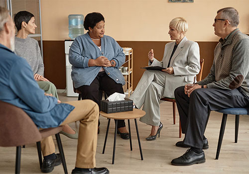addiction treatment specialist leading a group therapy session as part of an alcohol addiction treatment program