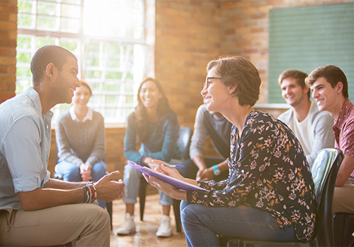 behavioral health therapist leads group of men and women in group therapy as part of an opioid detox program