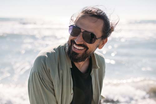 a man wearing sunglasses and smiling at the camera
