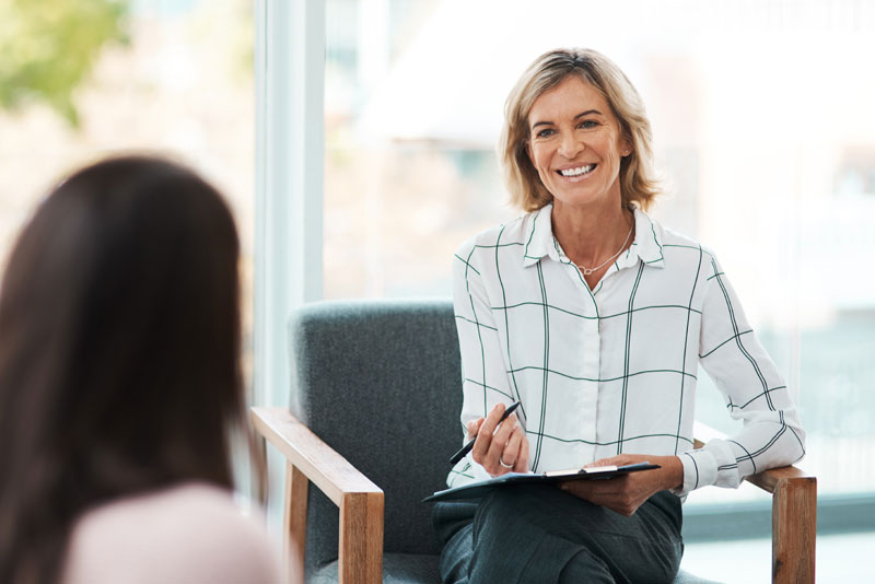 a woman sitting in a chair holding a clipboard and pen