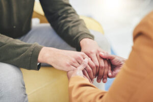 A woman participates in the methadone detox program at Next Step Recovery. She is clasping hands with her therapist.