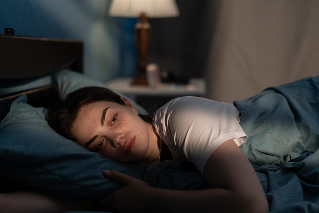 Woman lying in bed unable to sleep as the sun comes up